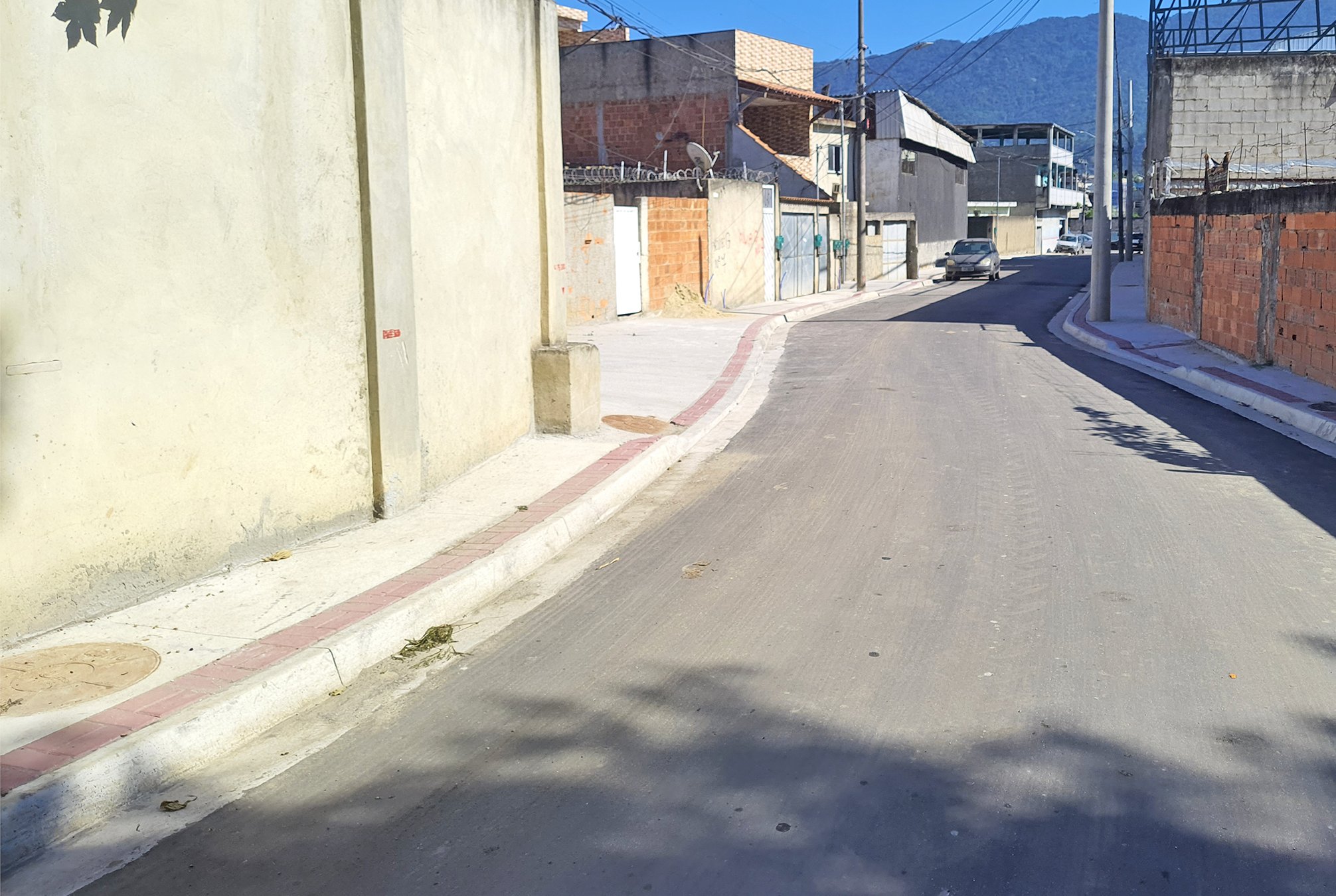 Rua em Vila Kennedy pavimentada, com calçada reconstruída e escoamento de água de chuva.