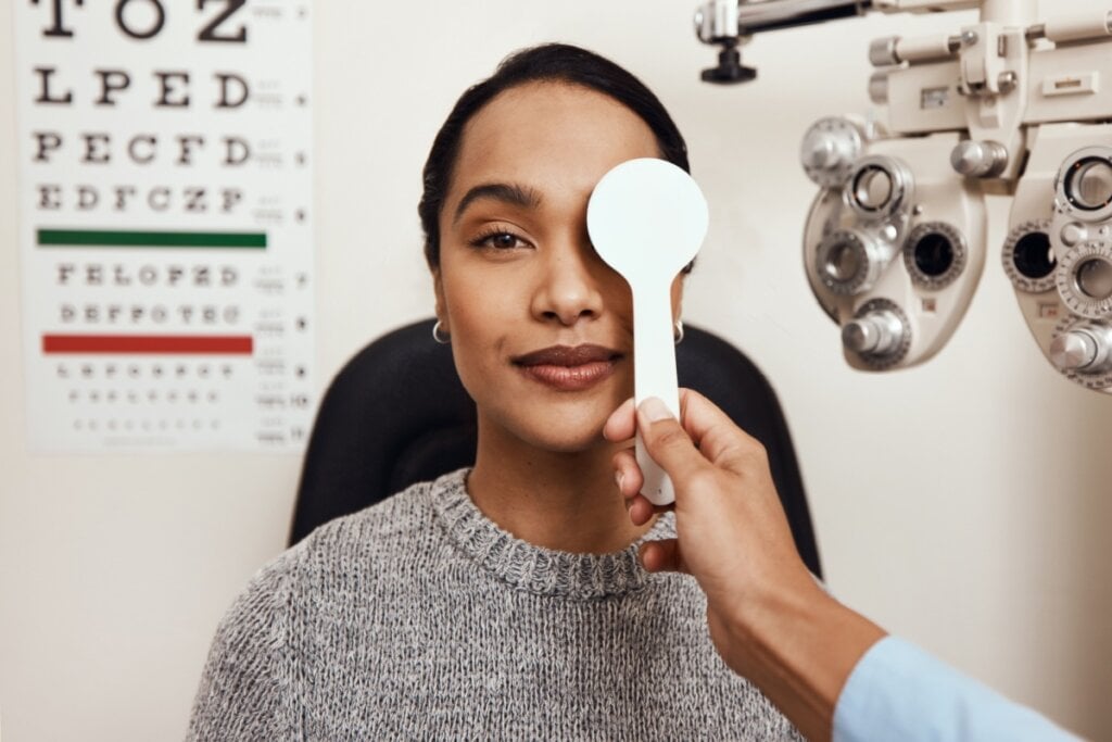 mão de médico tapando um dos olhos de mulher com ferramenta branca