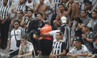 Fotógrafo é carregado para atendimento após ser atingido por bomba na beira do gramado da Arena MRV