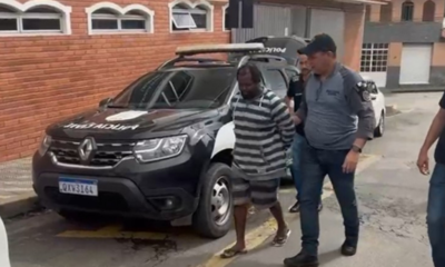 Homem preso por feminicídio é levado à delegacia por policiais.