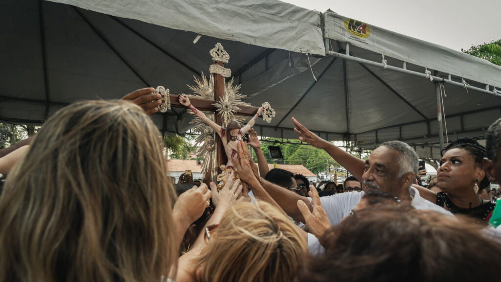 Fiéis estendem as mãos em direção a uma cruz com a imagem de Cristo, durante celebração religiosa na Lavagem do Senhor do Bonfim, em Salvador, Bahia