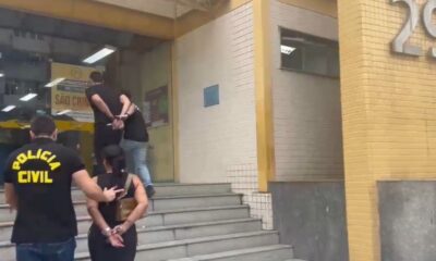 Reprodução de vídeo mostra casal de costas sendo escoltado por policiais civis entrando na delegacia de Madureira