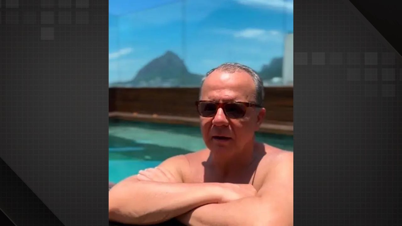 Imagem de Sérgio Cabral de óculos escuros, com os braços apoiados na borda de uma piscina. Ao fundo, é possível ver o Pão de Açúcar e o céu azul no Rio de Janeiro