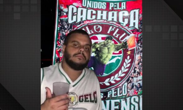 Torcedor do Fluminense morto à facadas aparece em foto segurando um copo e em frente a um banner da torcida.