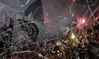 Torcida do Vasco em festa em São Januário, com bandeiras, papel picado e sinalizadores, em um ambiente de celebração