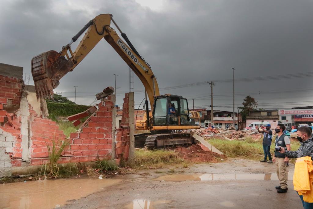 Imagem de uma retroescavadeira derrubando uma construção irregular