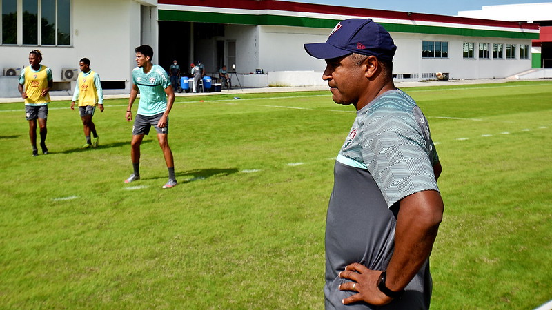 De boné roxo e camisa cinza, Roger Machado observa o treino do Fluminense