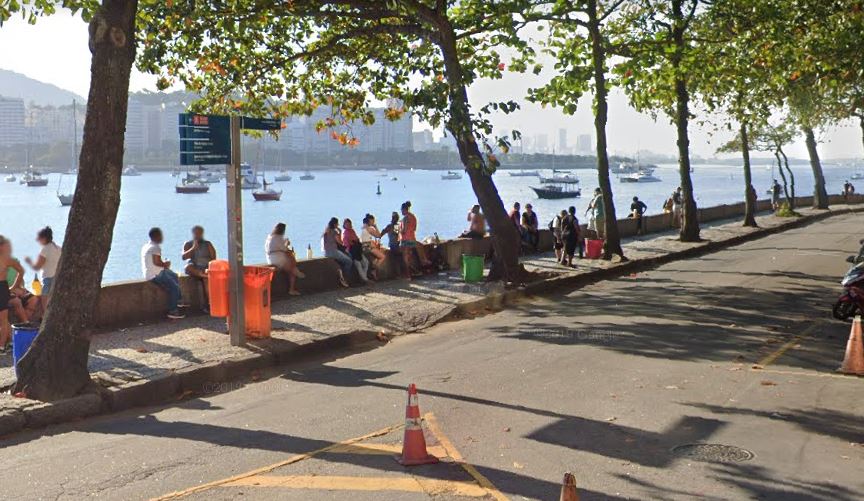 Pessoas sentadas na mureta da Urca