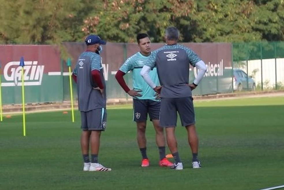 O lateral Marlon está entre dois integrantes da comissão técnica do Fluminense  no campo de treinamento