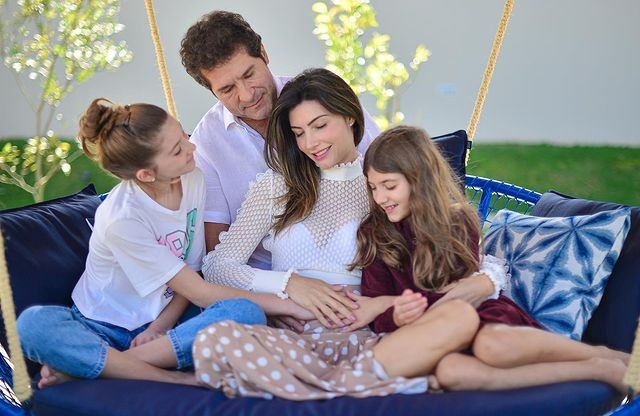 Daniel com a esposa e as filhos no sofá anunciando terceira gravidez