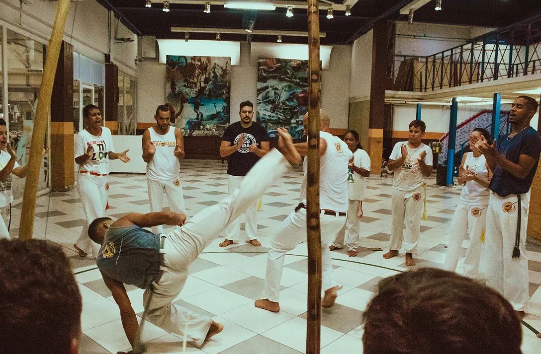 Na imagem, pessoas praticando capoeira