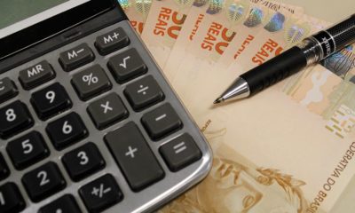 Imagem de uma calculadora, dinheiro e caneta