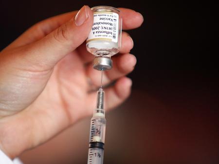 Mão de uma médica segurando um frasco de vacina